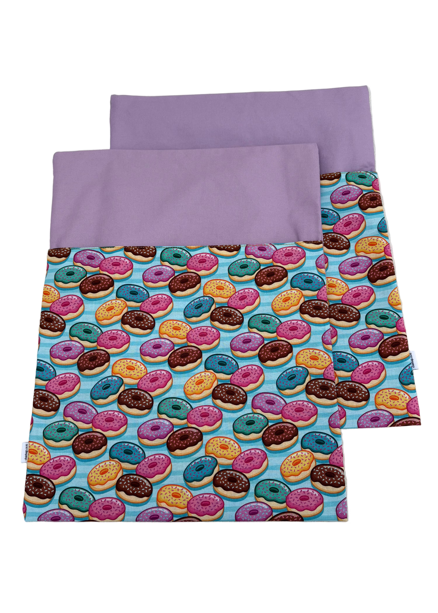 Two fabric swatches, one with a colorful donut pattern and the other purple, on a white surface.Two fabric swatches, one with a colorful donut pattern and the other purple, on a white surface.